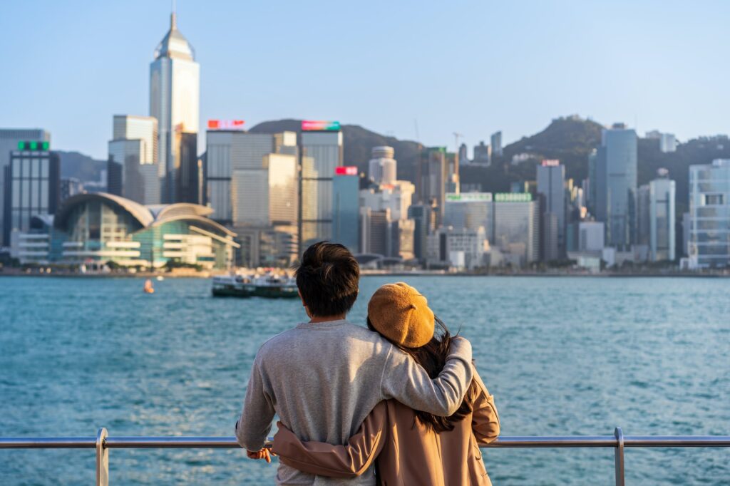 Young couple traveler relaxing and enjoying the sunset atmosphere at Victoria harbour in Hong Kong